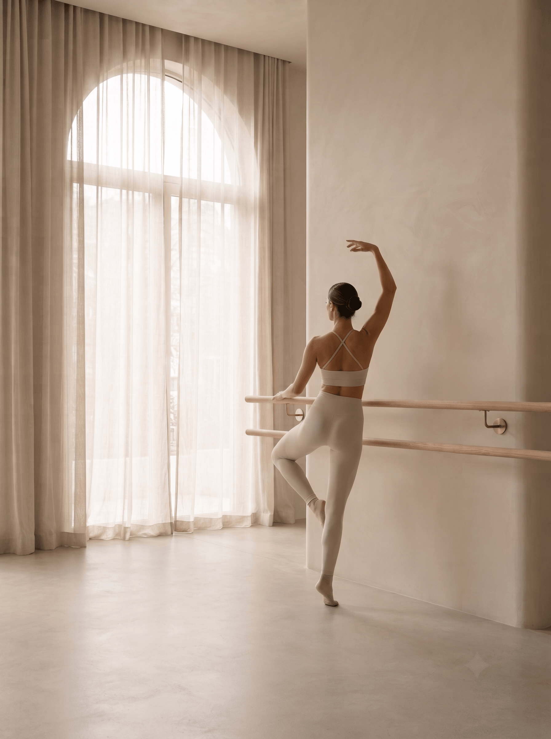 Professional Barre studio interior with a woman practicing at a light wood barre